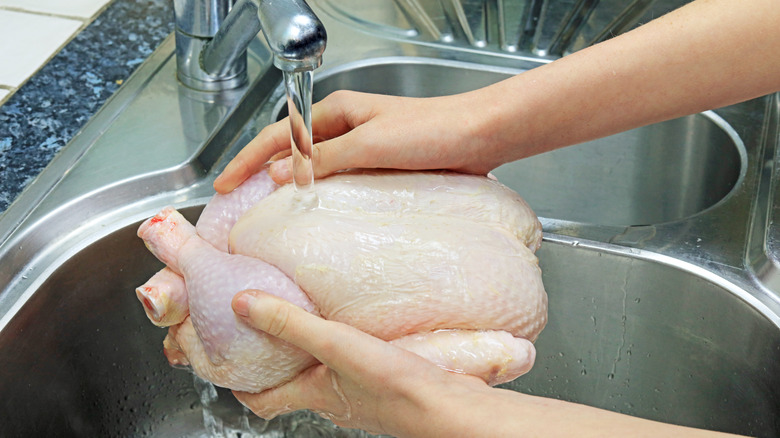 raw chicken under running water