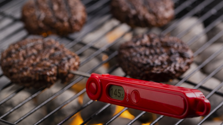 person using a meat thermometer on burger