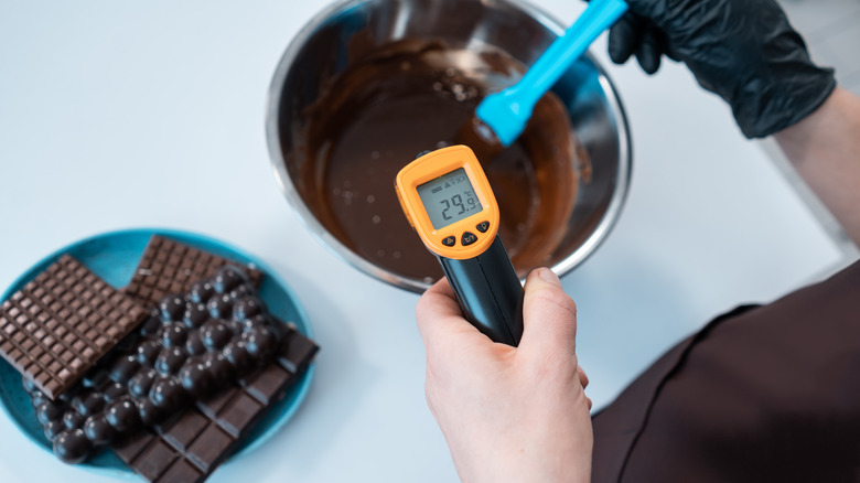 Chef checking melted chocolate with a candy thermometer