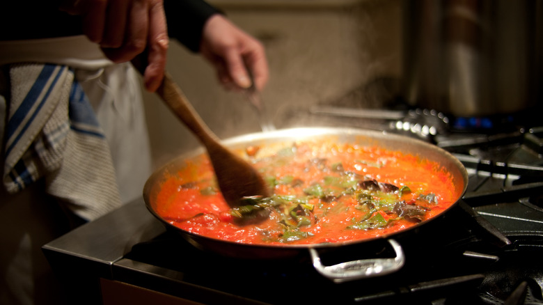 chef stirring sauce on stove