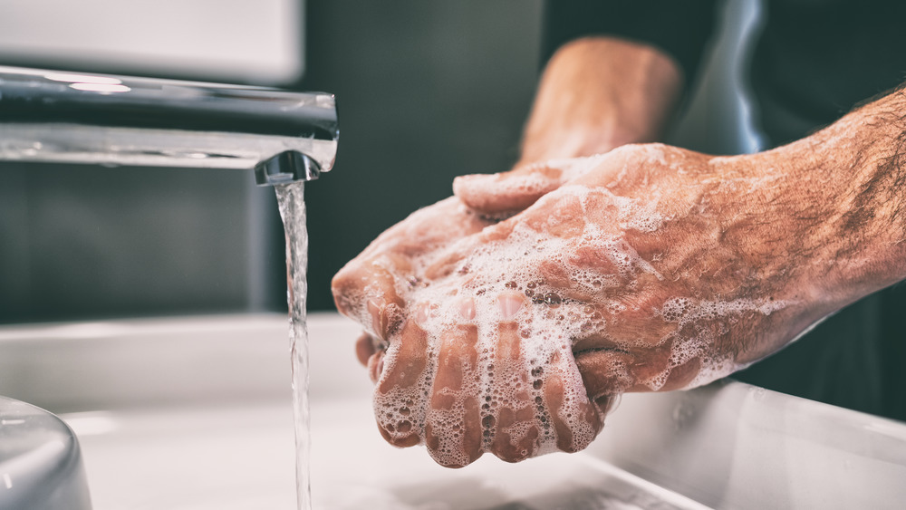 man washing hands at sink