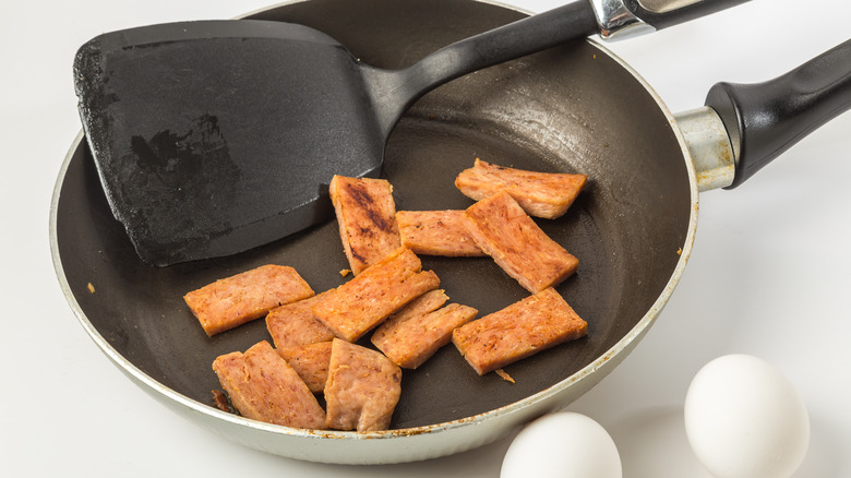 Spam strips in skillet with spatula