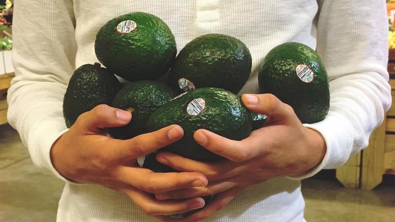 holding many avocados