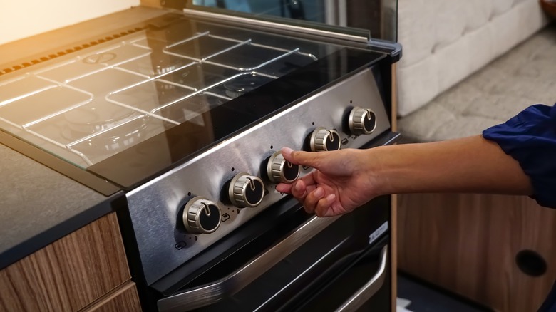 Hand turning dial on oven