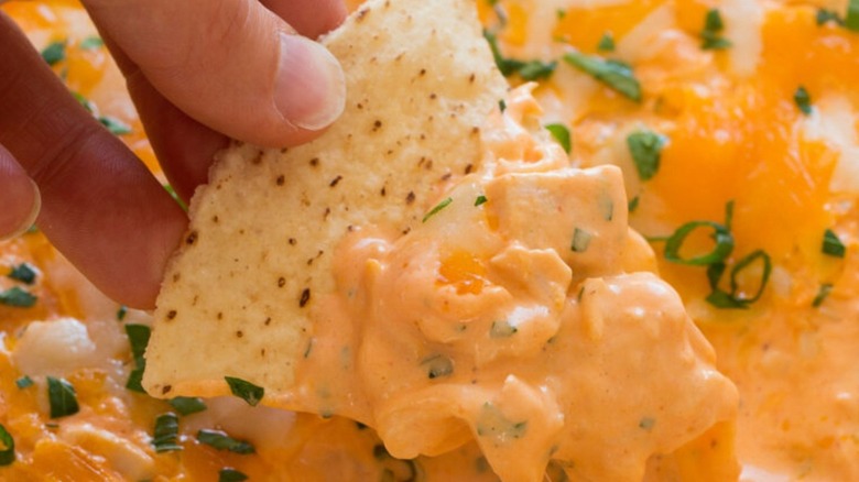 Hand scooping Buffalo dip onto chip