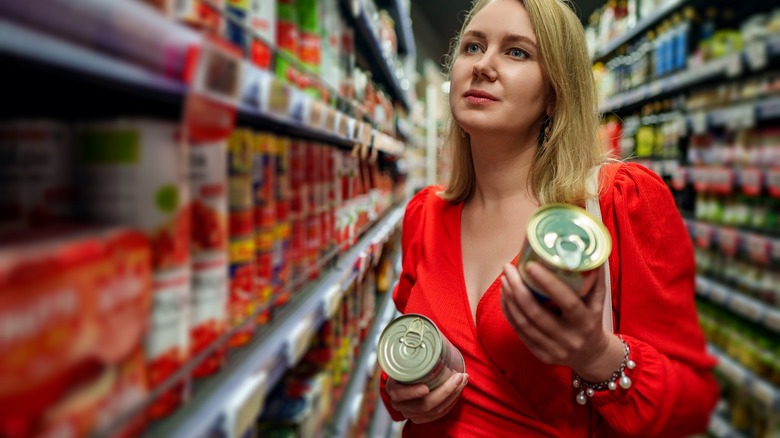 shopper choosing canned tomatoes