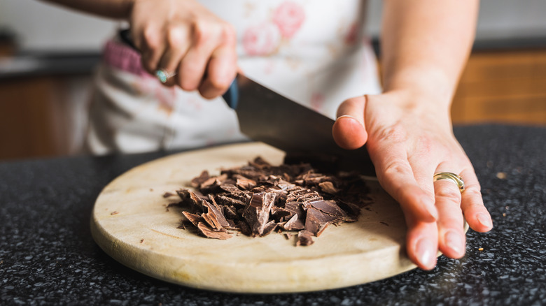 Hands chopping chocolate on wooden board