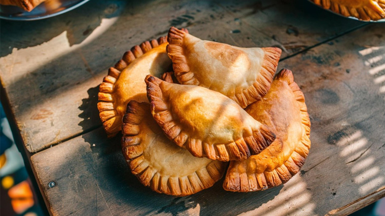 A pile of empanadas on a wooden table