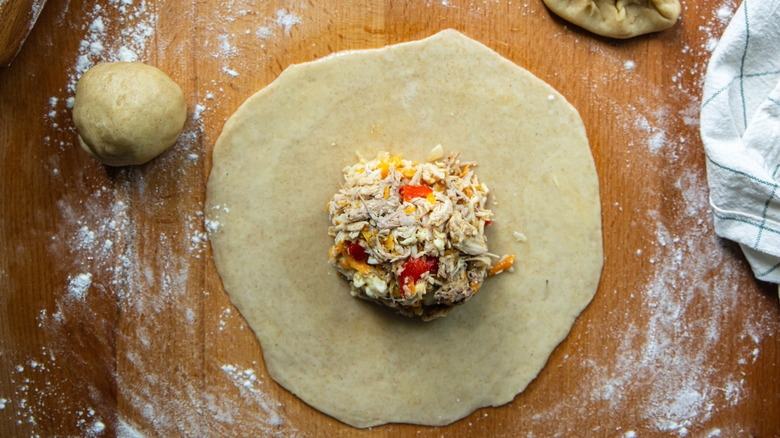 Rolled out empanada dough with filling on top