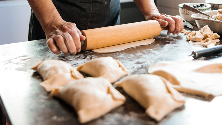 A person rolling empanada dough