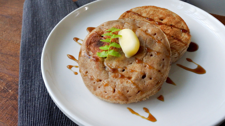 Homemade crumpets with butter and honey on a white plate