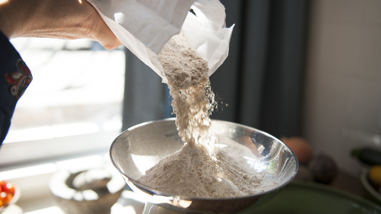 Person weighing flour on kitchen scale