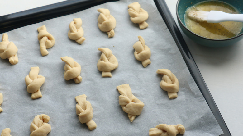 Shaped garlic knots on parchment paper on a sheet pan