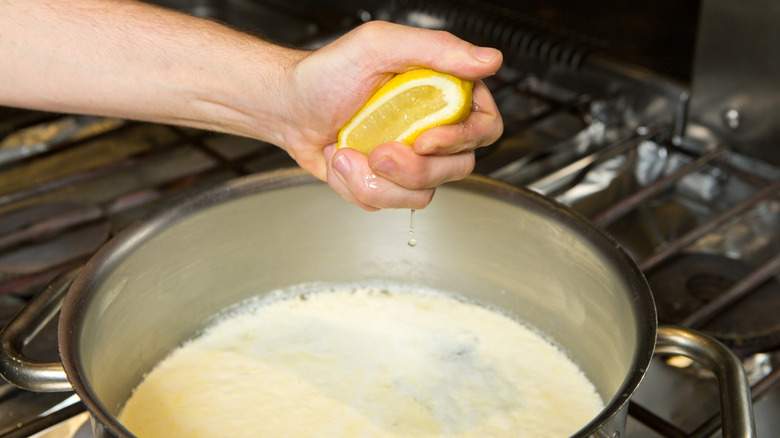 Hand squeezing lemon into pan