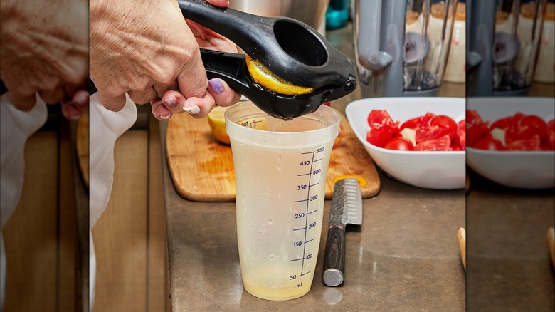 Lemon being squeezed into measuring cup