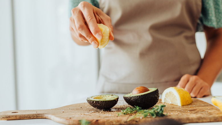 Lemon being squeezed onto avocado