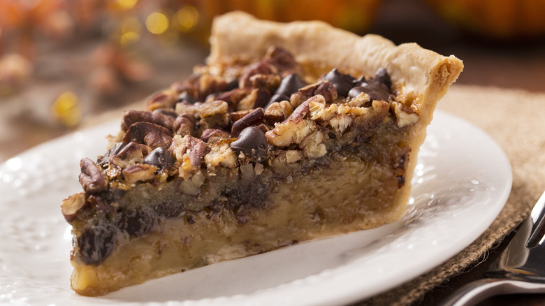 Slice of chocolate pecan pie on white plate