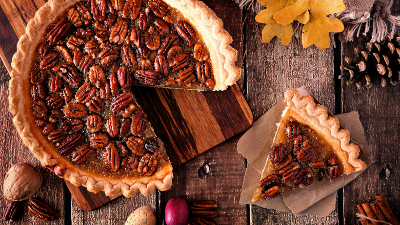 Pecan pie and slice on wooden table