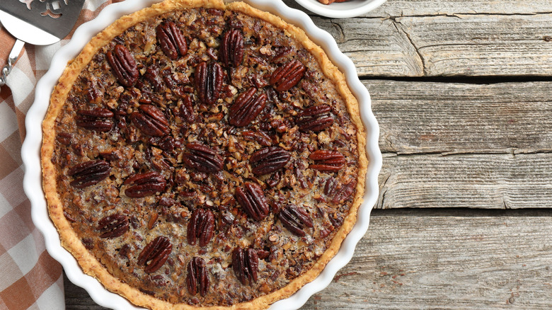 Pecan pie in pan on table with gingham napkin