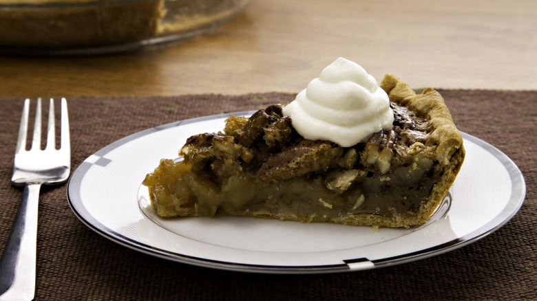 Slice of pecan pie on plate and fork