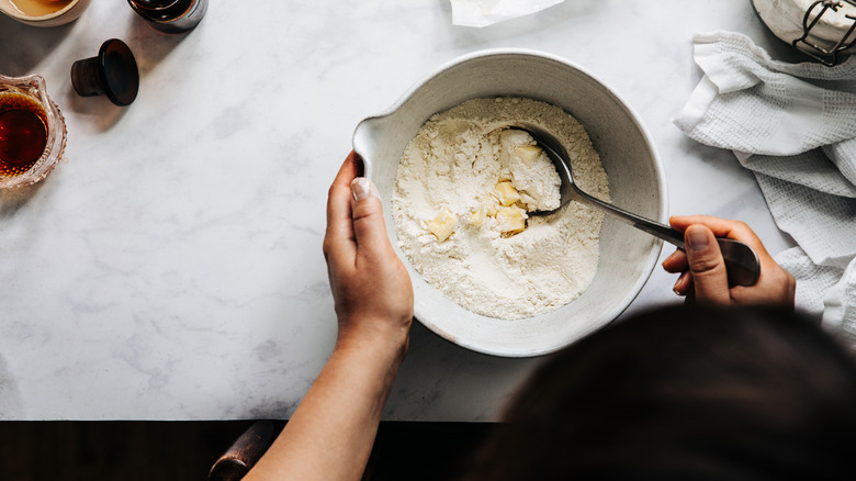 A person mixing flour and butter in a bowl