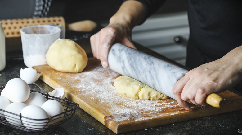 A person using a rolling pin on pastry dough