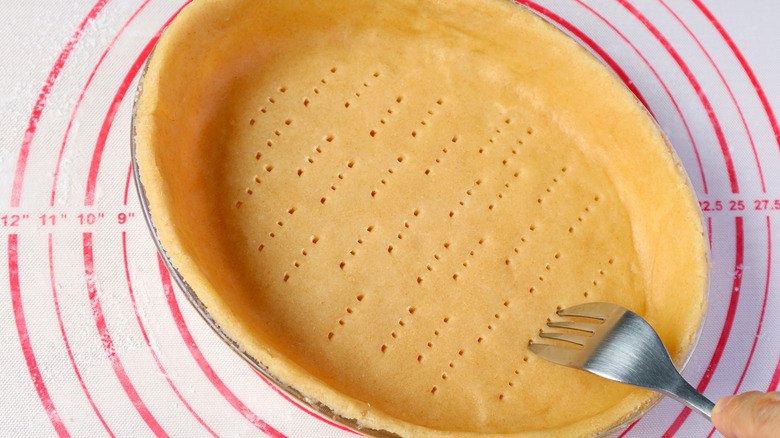 A fork being used to poke holes in a pie crust