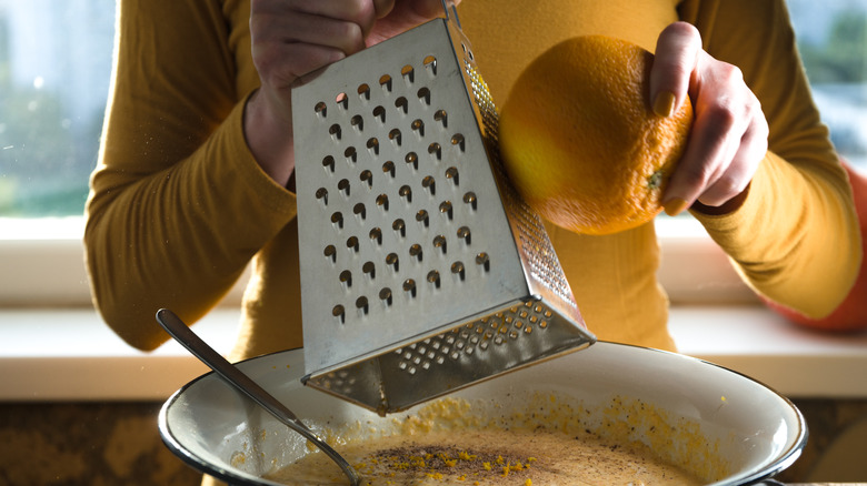 person zesting orange with box grater