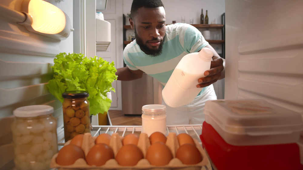 man getting milk from fridge