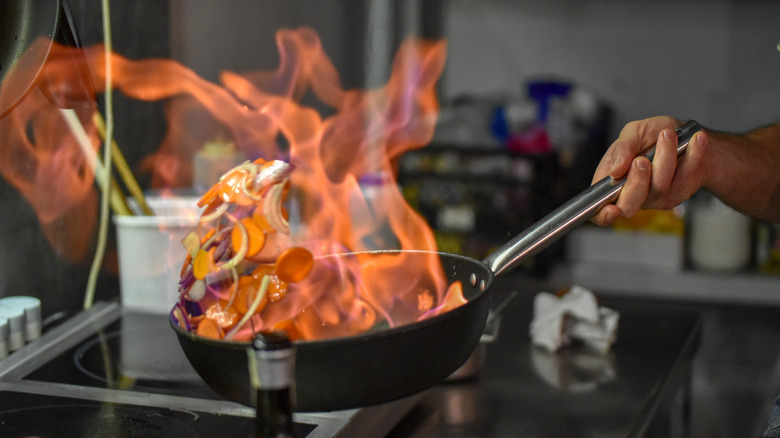 person flambéing on stove