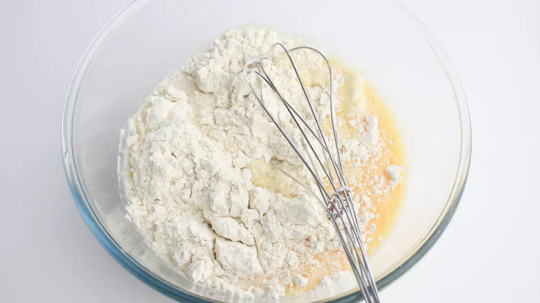 Flour in bowl with whisk and liquids