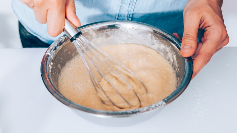 Whisking lumpy batter in a bowl