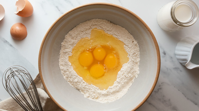 Eggs broken into well in flour in bowl