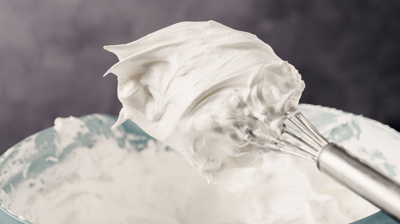 Whipped egg whites in a bowl with a whisk