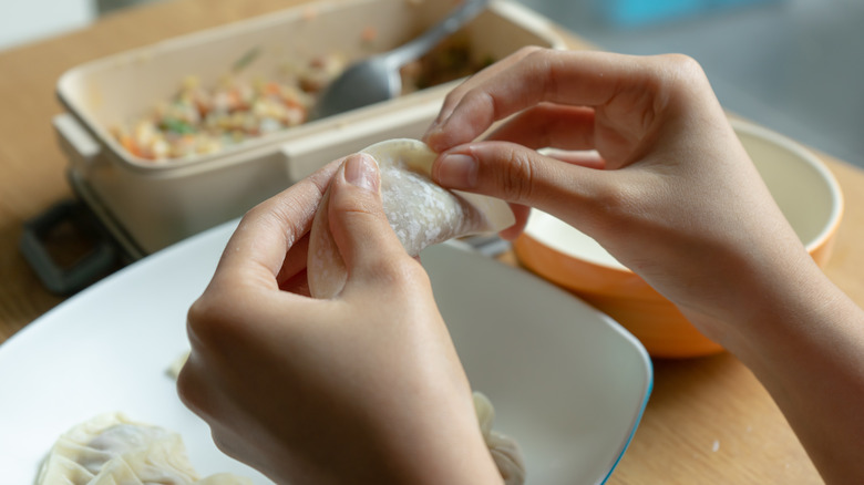 hands pinching dumpling wrapper closed