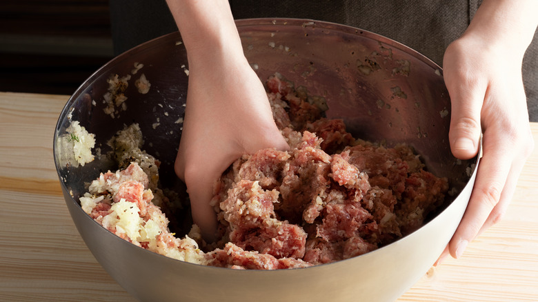 hand mixing ground meat in bowl