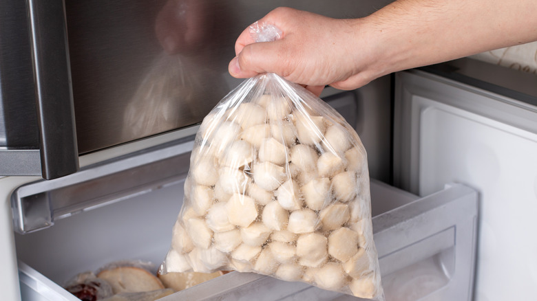 hand pulling bagged frozen dumplings from freezer