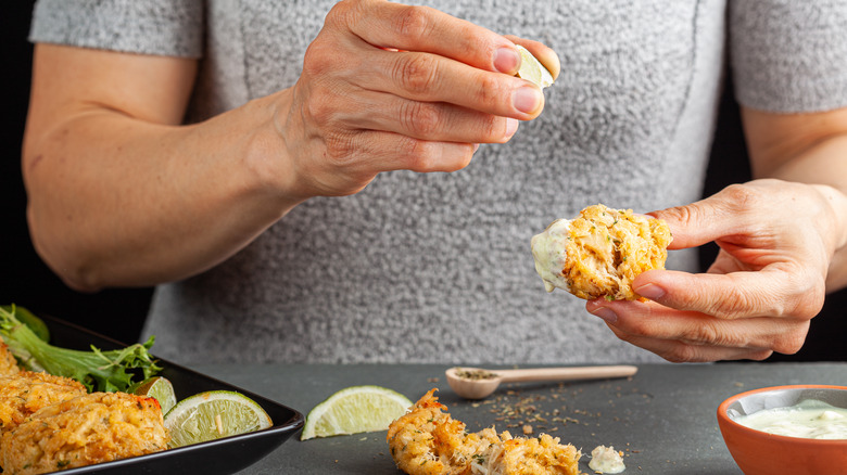 hand squeezing lime onto crab cake