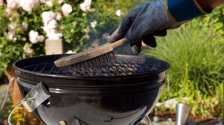 Person cleaning their grill with a glove on