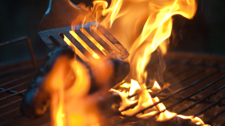 Burnt sausage being flipped on the grill