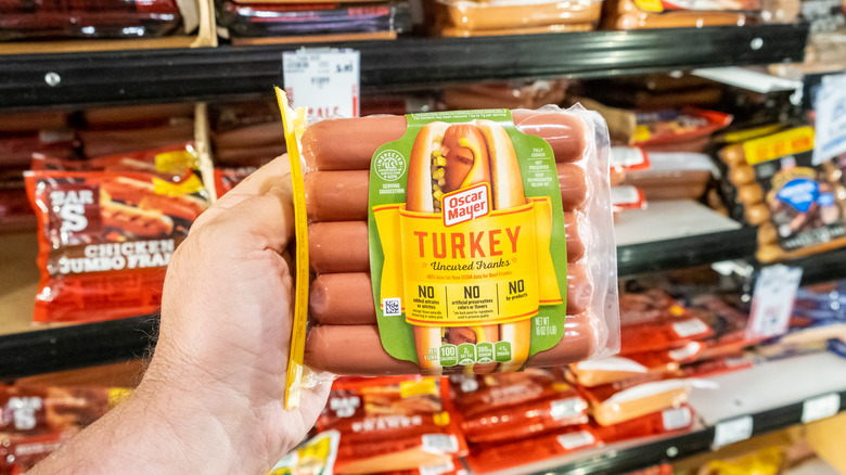 person holding hot dogs in store 