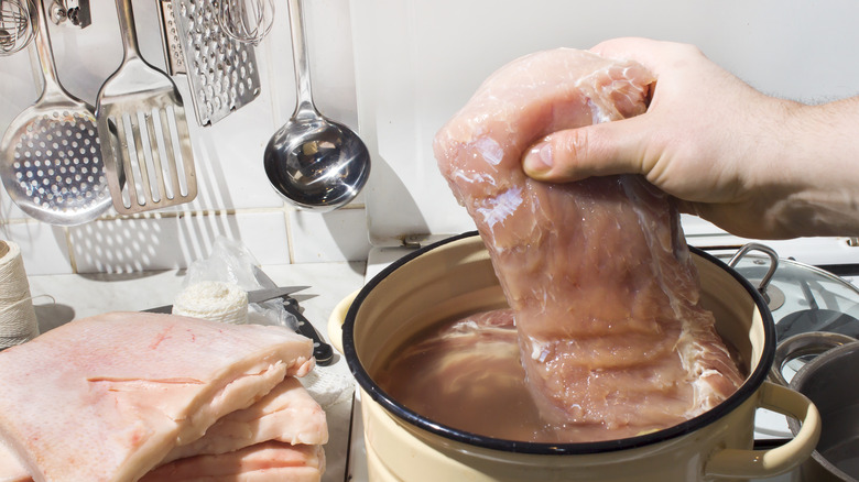 hand holding meat in a brine