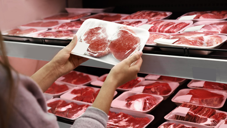 handing holding plastic wrapped package of pork