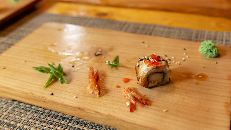 one piece of sushi left on wooden board