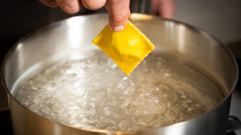 cook dropping ravioli into pot