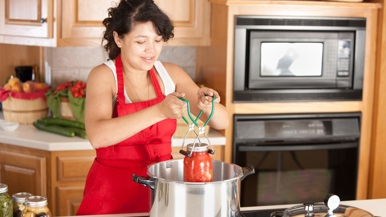 woman lowering jar into pot