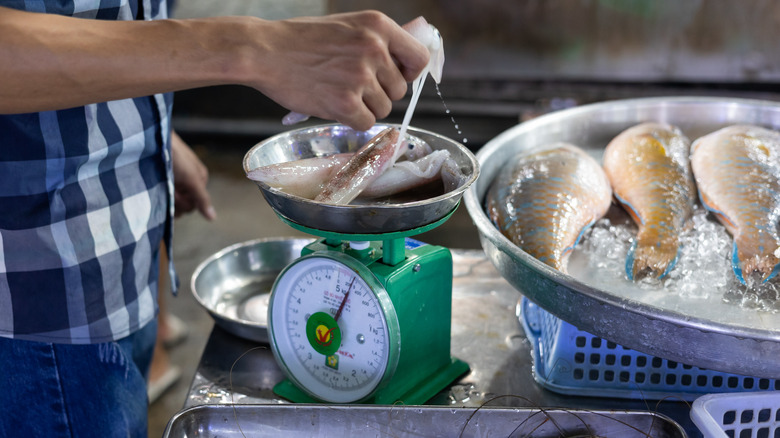 Fishmonger weighing raw squid