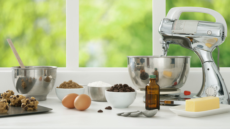 mixer and bowls on counter with unbaked cookies