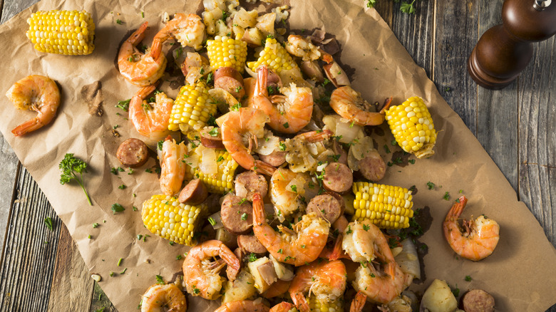 Shrimp, sausage, potatoes, and corn cobs on butcher paper on table