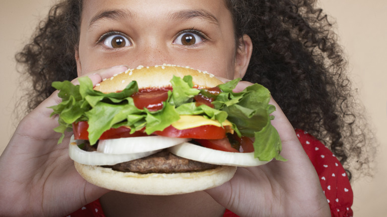 person eating a burger filled with salad